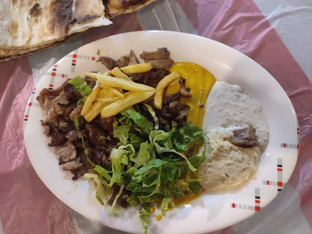 Camel meat shawarma in a plate with chips and sauces