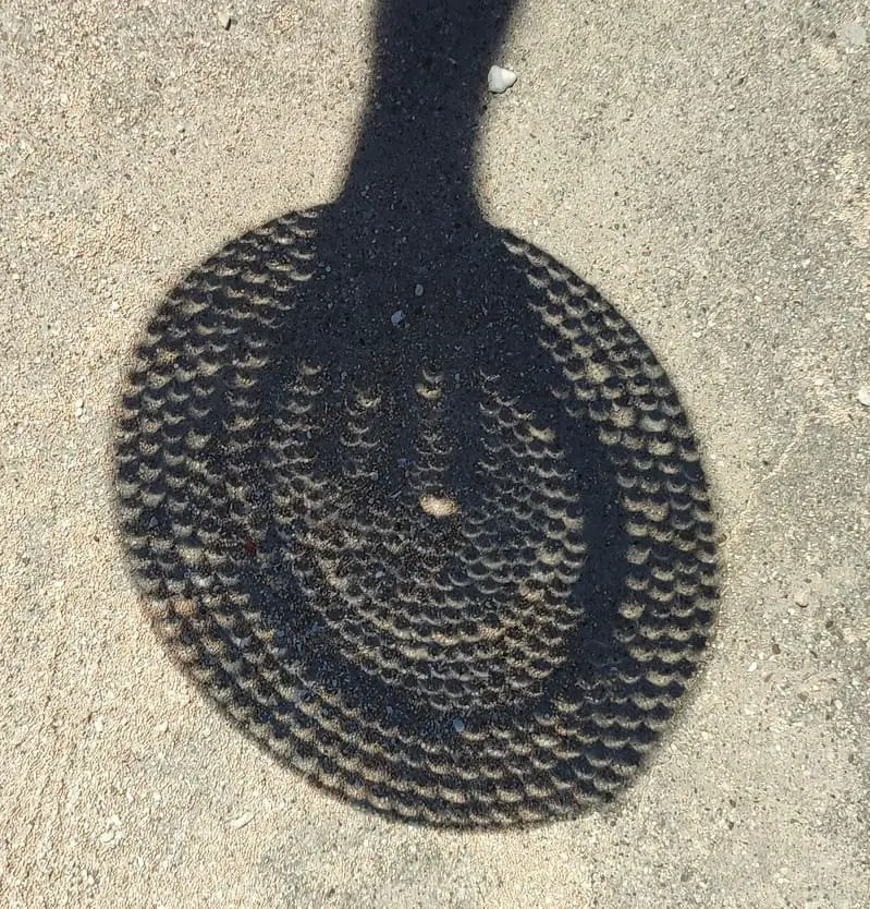Sun shade crescent shape during eclipse through small holes in a hat.