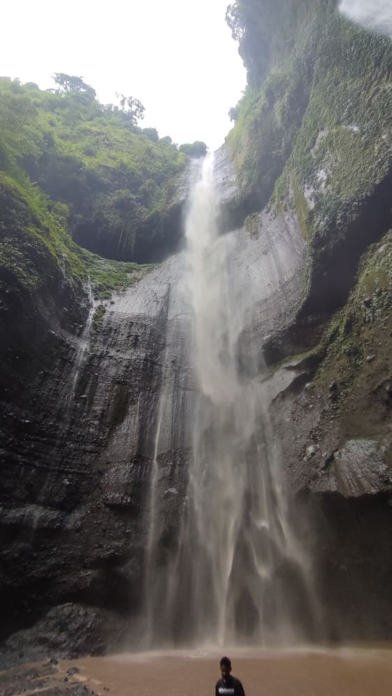 the tall Madakaripura Waterfall from below