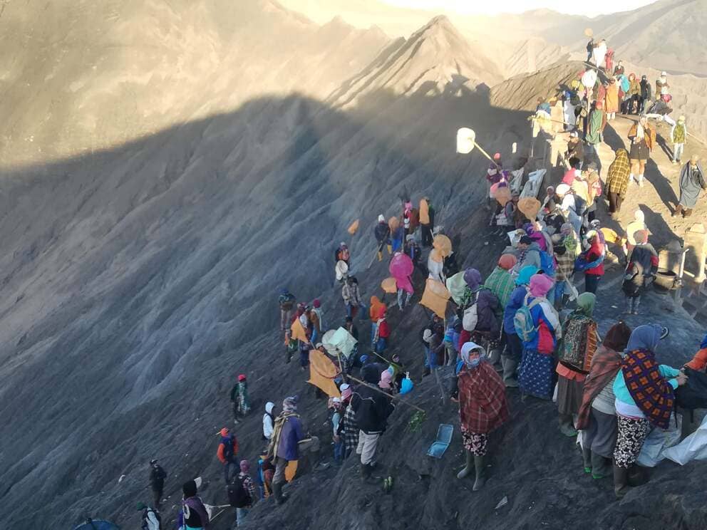 Tenggerese men trying to catch items thrown inside Mount Bromo's crater