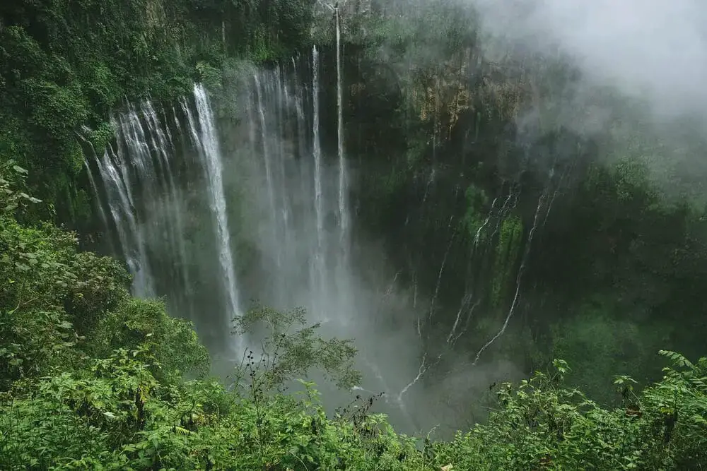 Aerial picture of Tumpak Sewu waterfall - a must visit when backpacking in Java and mount Semeru in the background.