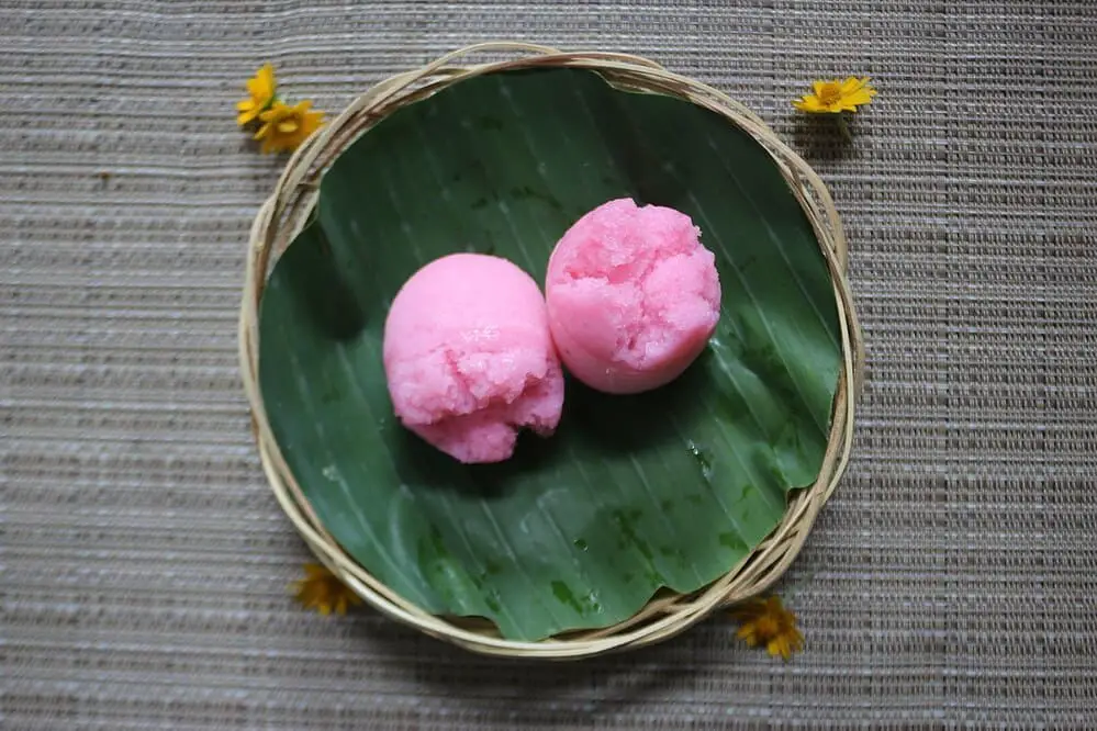 Two pink kue apem in a tray
