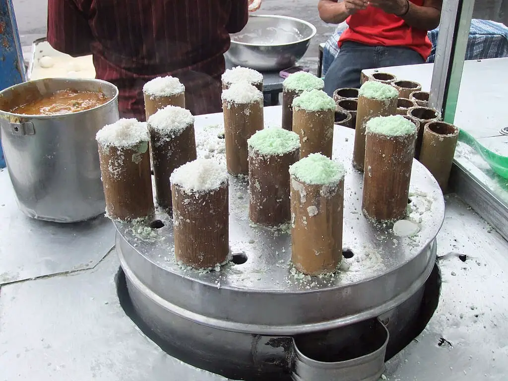 Kue putu in bamboo rolls on a rotating mechanism to be steamed