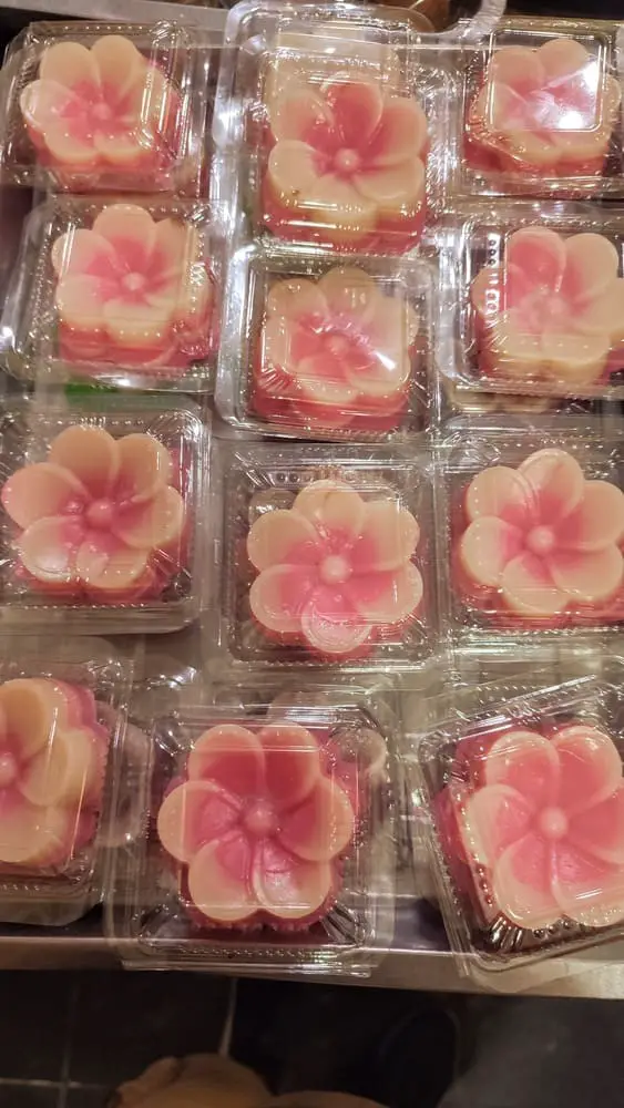 A tray of individually packaged kue talam in the shape of pink and white roses
