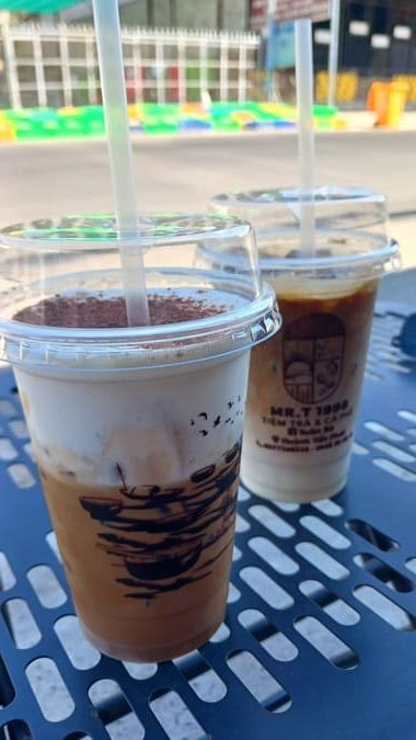 Two plastic cups of coffee, one of cafe muoi, one of cafe sua from a street coffee stall