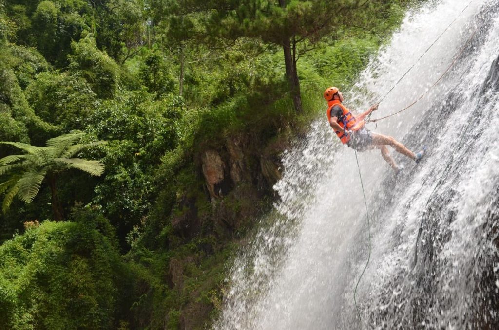 A man descending down a waterfall using a rope