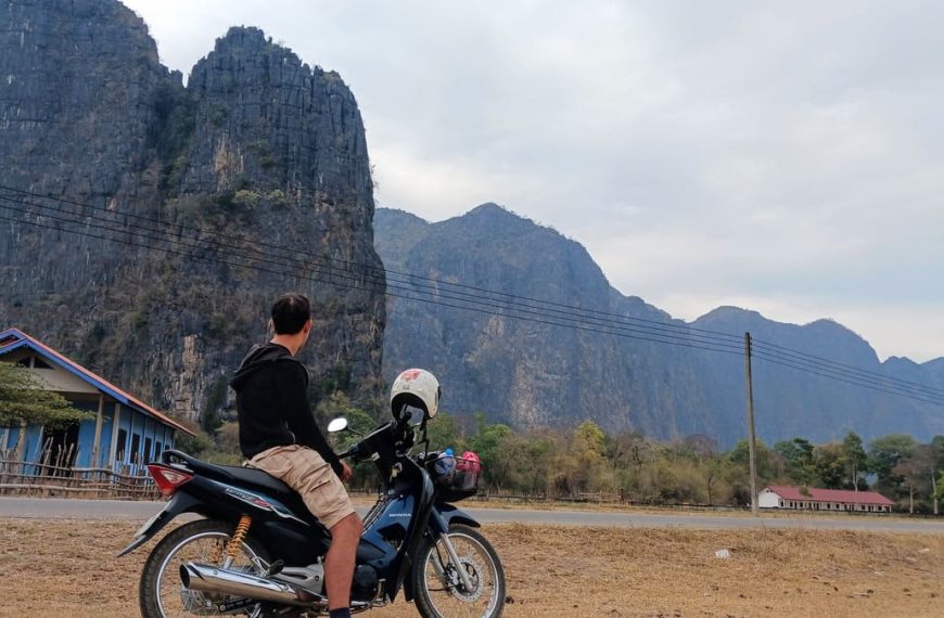 Simon sitting on a motorcycle looking at the mountains around Kong Lor