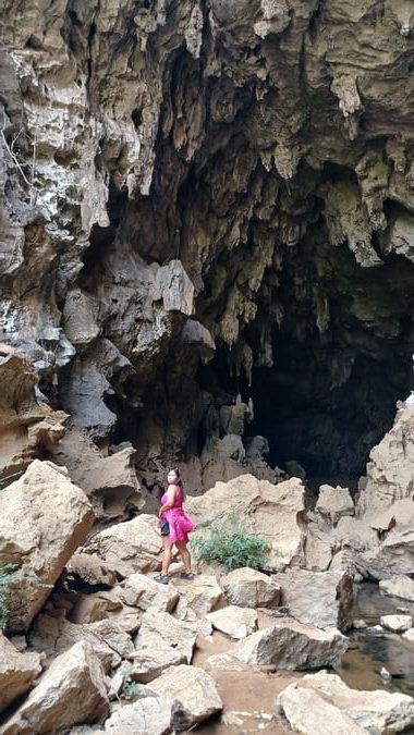 a woman in a pink dress standing in a cave