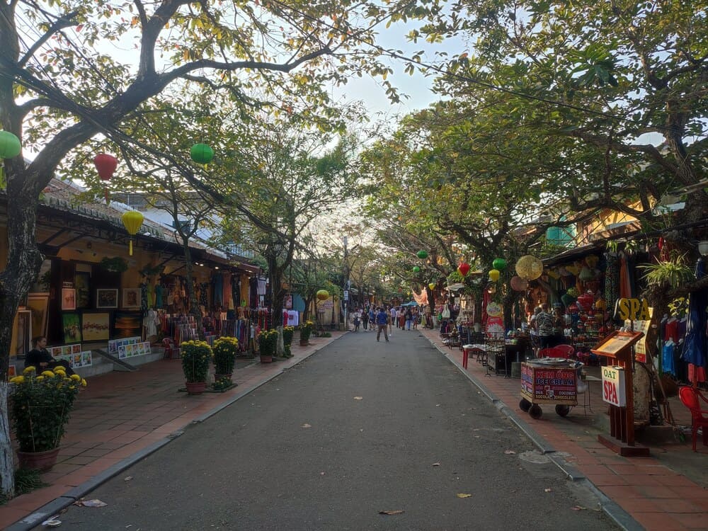 a relatively empty street in Hoi An with vendors on both sides