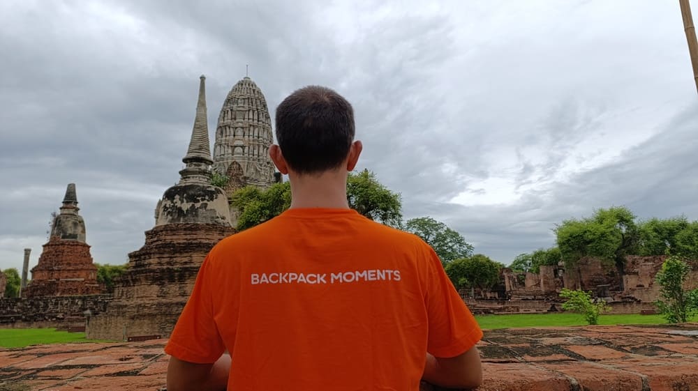 Simon wearing a t-shirt with the caption "Backpack Moments" looking at ancient temples in Ayutthaya