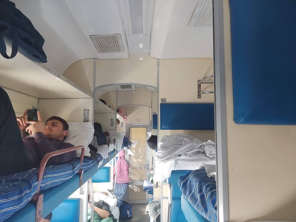 Inside a sleeper train in Uzbekistan with berths and people on them