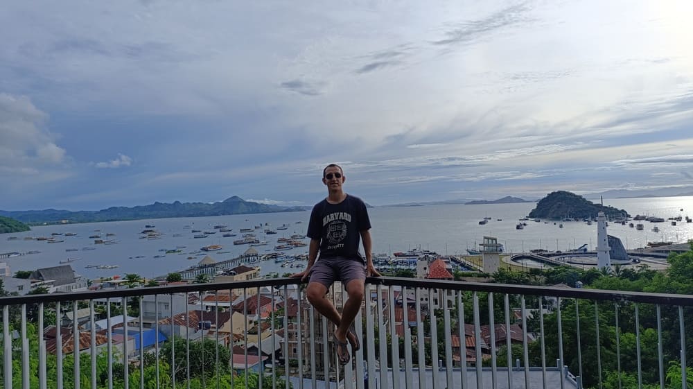 Simon sitting on a fence overlooking Labuan Bajo harbor