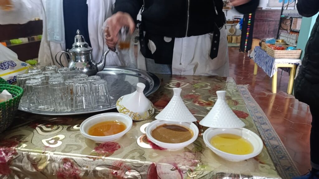 A table with glasses and small containers filled with argan oil, honey, and other toppings.
