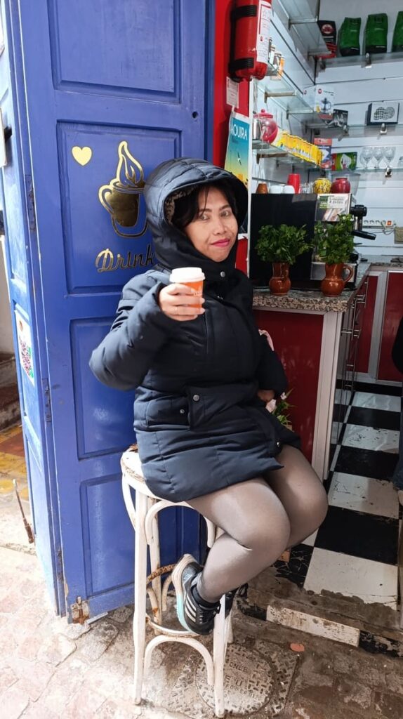 Yulli enjoying a cup of coffee on a chair next to a small coffee shop in Essaouira